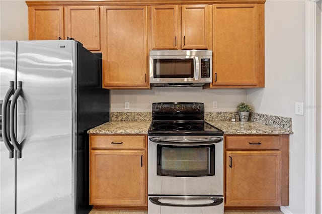 kitchen featuring appliances with stainless steel finishes and light stone counters