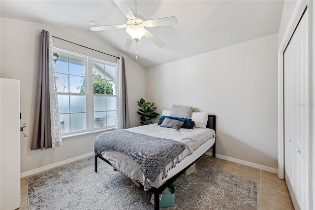 bedroom with lofted ceiling, light tile patterned floors, baseboards, and a closet