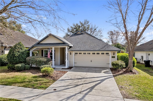 view of front of house with roof with shingles, covered porch, an attached garage, a front yard, and driveway