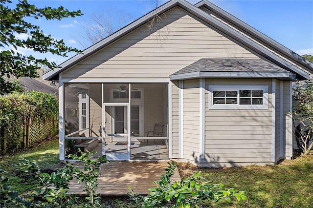 rear view of house with a shingled roof, fence, and a sunroom