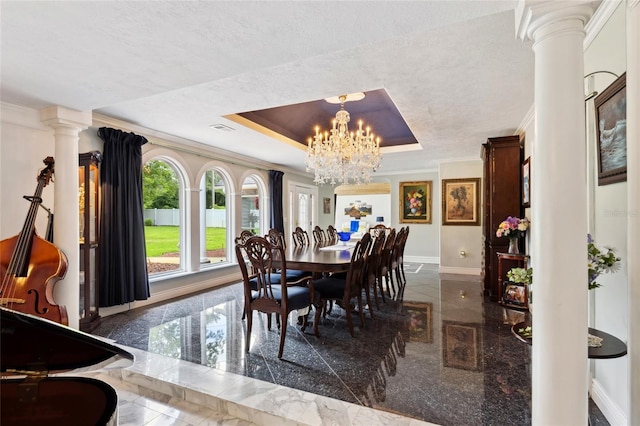 dining area featuring a tray ceiling, crown molding, baseboards, granite finish floor, and ornate columns