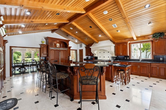 kitchen with a kitchen island, a kitchen breakfast bar, backsplash, custom exhaust hood, and a wealth of natural light