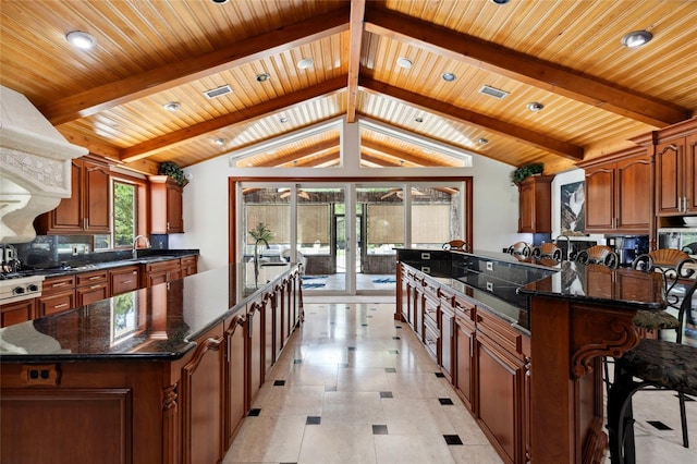 kitchen with a spacious island, backsplash, brown cabinets, and lofted ceiling with beams