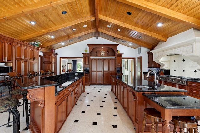 kitchen featuring stainless steel appliances, premium range hood, a breakfast bar, a spacious island, and a sink