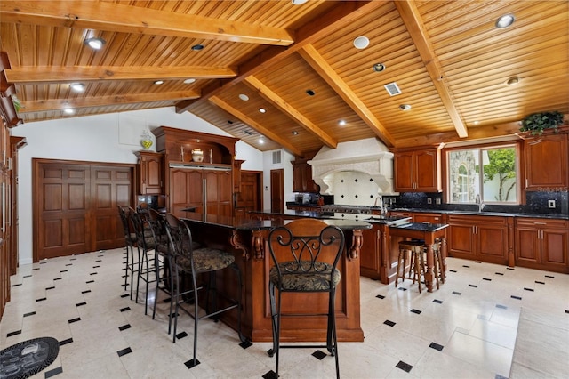 kitchen with beam ceiling, a spacious island, tasteful backsplash, custom range hood, and a kitchen breakfast bar