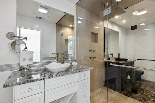 bathroom with a shower stall, visible vents, tile walls, and vanity