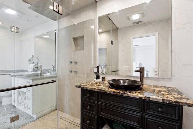 full bath with a shower stall, visible vents, tile walls, and vanity