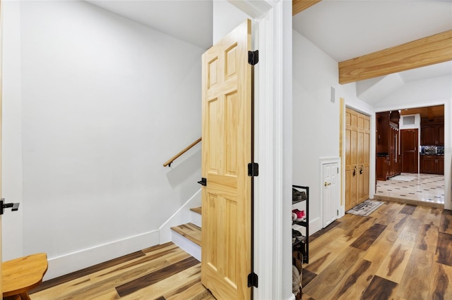 staircase featuring lofted ceiling with beams, baseboards, and wood finished floors