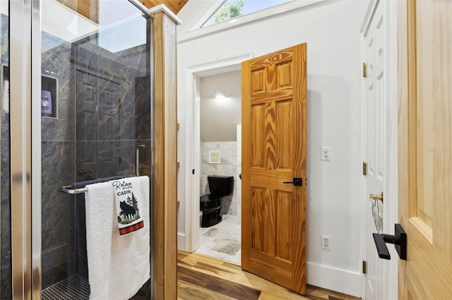 full bath with a stall shower, wood finished floors, and tile walls