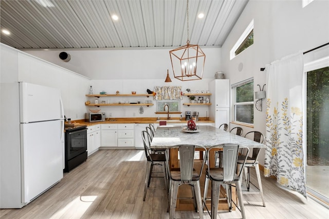 kitchen with black range with electric stovetop, freestanding refrigerator, a kitchen bar, white cabinetry, and open shelves