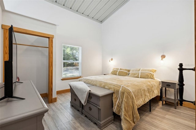 bedroom with light wood-type flooring, lofted ceiling, and baseboards