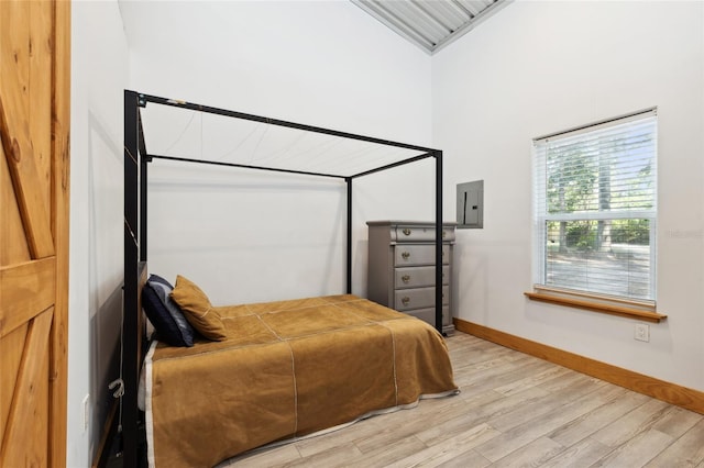 bedroom featuring baseboards, electric panel, and light wood-style floors