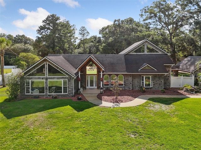 view of front of property featuring stone siding, fence, and a front yard