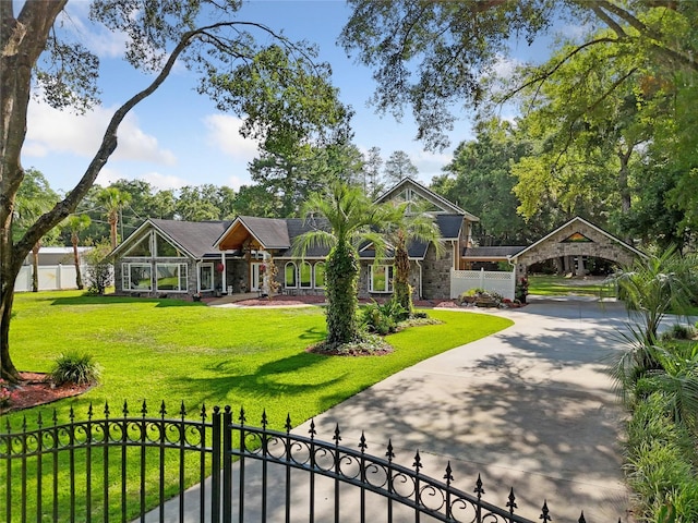 view of front of home featuring stone siding, a fenced front yard, a front lawn, and concrete driveway