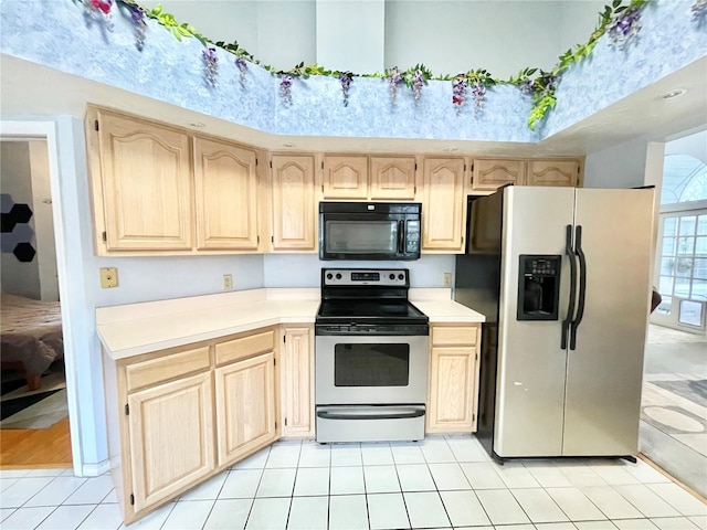 kitchen with light tile patterned floors, light brown cabinets, appliances with stainless steel finishes, and light countertops