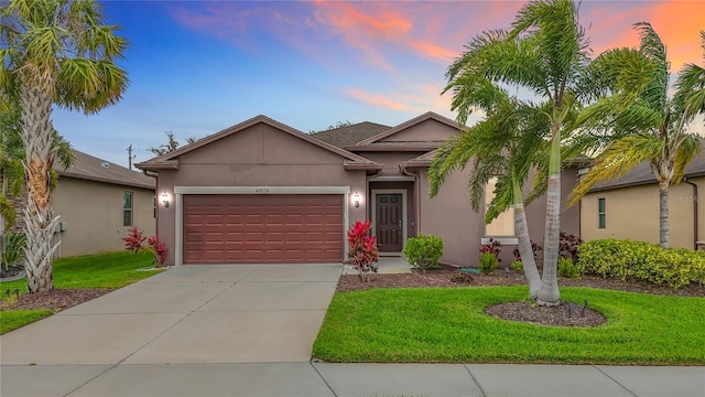 single story home with a garage, driveway, a front yard, and stucco siding