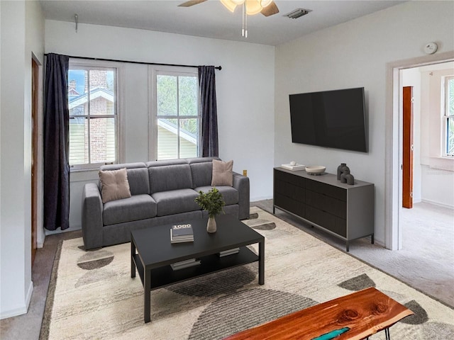 living room with light colored carpet, a ceiling fan, baseboards, and visible vents