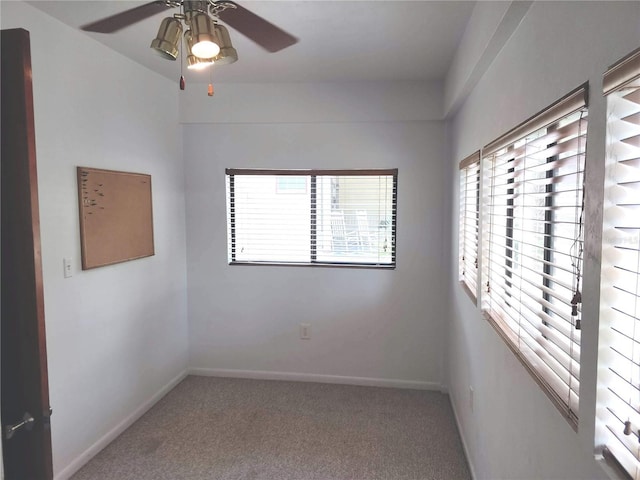 carpeted empty room featuring baseboards and a ceiling fan