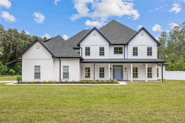 modern inspired farmhouse featuring covered porch, a front lawn, a shingled roof, and fence