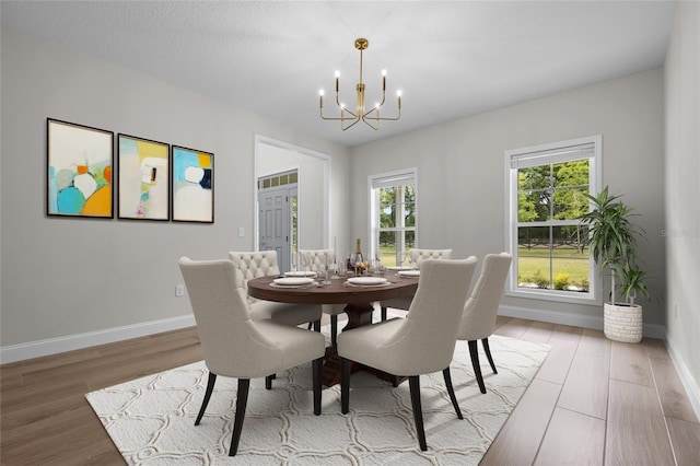 dining space featuring wood finished floors, baseboards, and an inviting chandelier