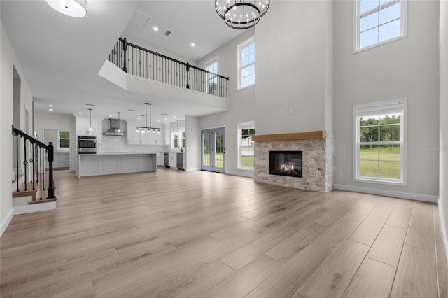 unfurnished living room with a wealth of natural light, a fireplace, light wood-style flooring, and stairs