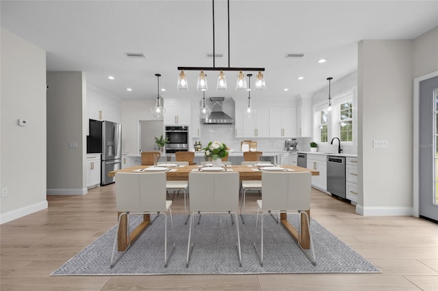 dining space with light wood-style flooring, visible vents, and baseboards