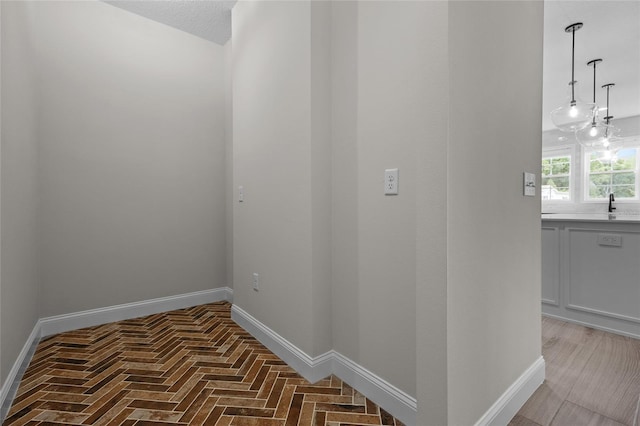 hallway featuring brick floor and baseboards