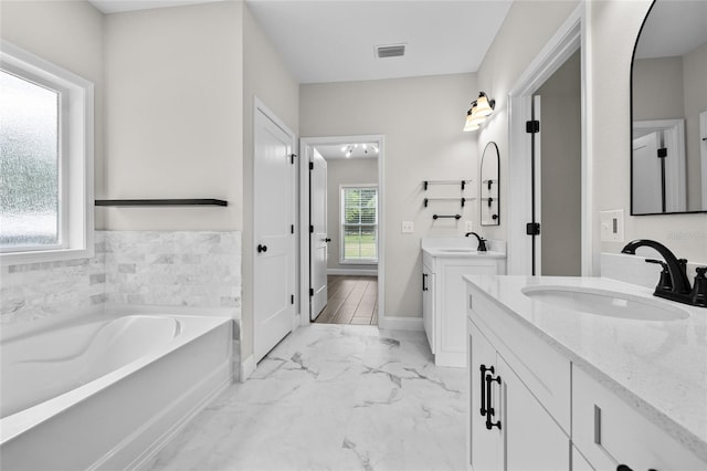 full bath with two vanities, a sink, baseboards, marble finish floor, and a bath