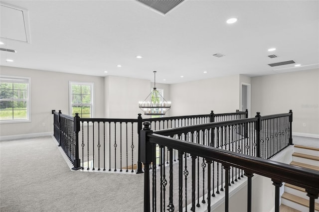 corridor featuring carpet flooring, visible vents, an upstairs landing, baseboards, and attic access