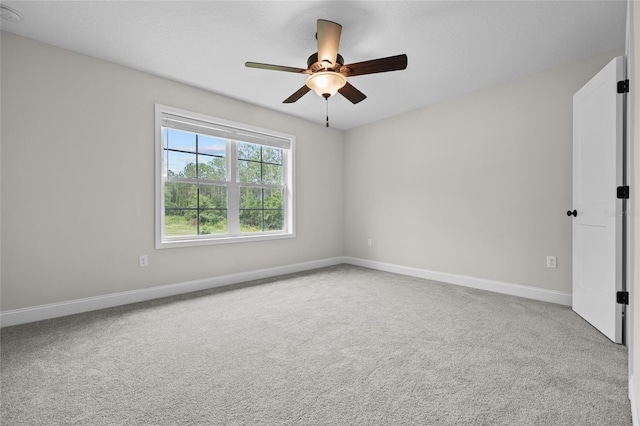 carpeted spare room with a ceiling fan and baseboards