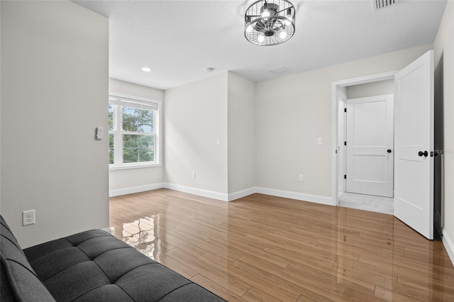 unfurnished living room with visible vents, light wood-style flooring, baseboards, and a textured ceiling