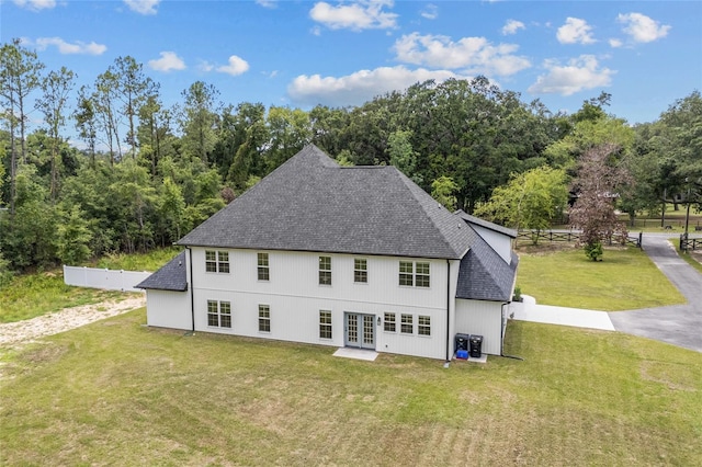 rear view of house with cooling unit, fence, a yard, french doors, and roof with shingles