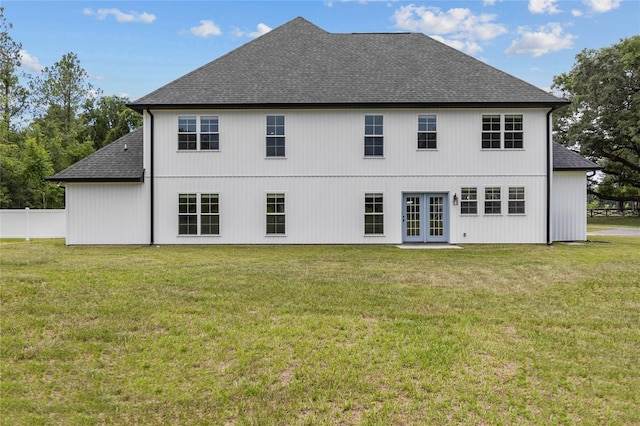 rear view of house featuring a shingled roof, french doors, a lawn, and fence