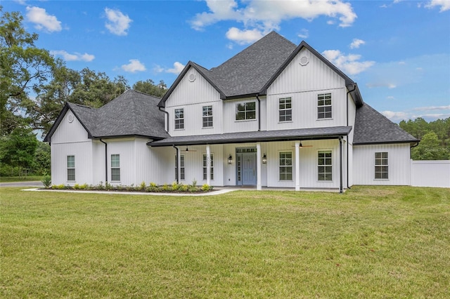 modern farmhouse style home featuring covered porch, a front lawn, roof with shingles, and fence