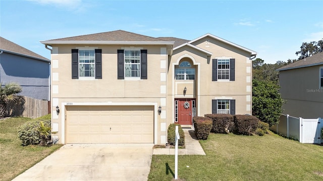 traditional-style home with concrete driveway, an attached garage, fence, a front lawn, and stucco siding