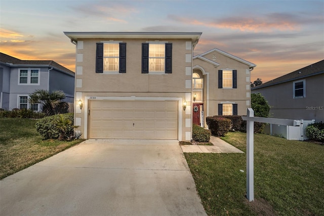 traditional-style home with a yard, stucco siding, concrete driveway, fence, and a garage