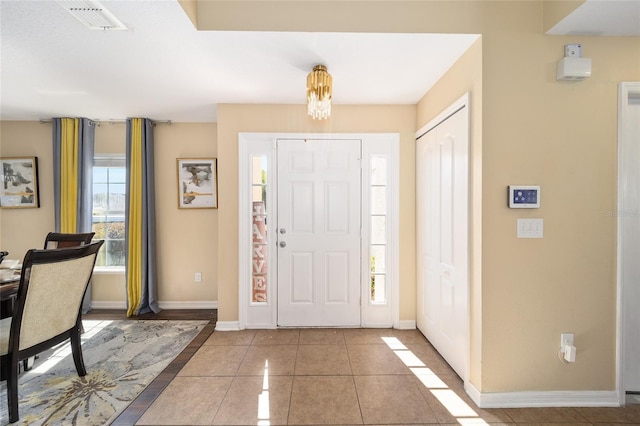 tiled entryway featuring baseboards and visible vents