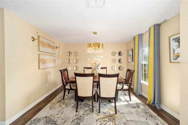 dining space with baseboards, wood finished floors, visible vents, and a notable chandelier