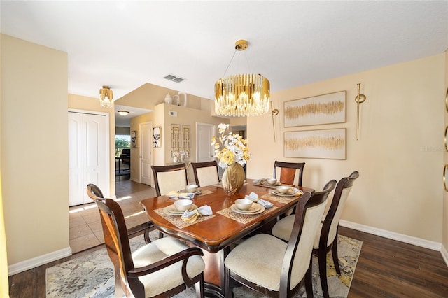 dining space with an inviting chandelier, visible vents, baseboards, and wood finished floors