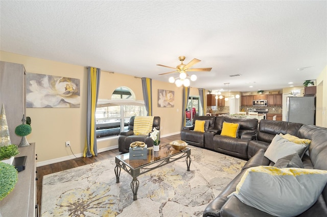 living room with a textured ceiling, dark wood-style flooring, visible vents, and baseboards