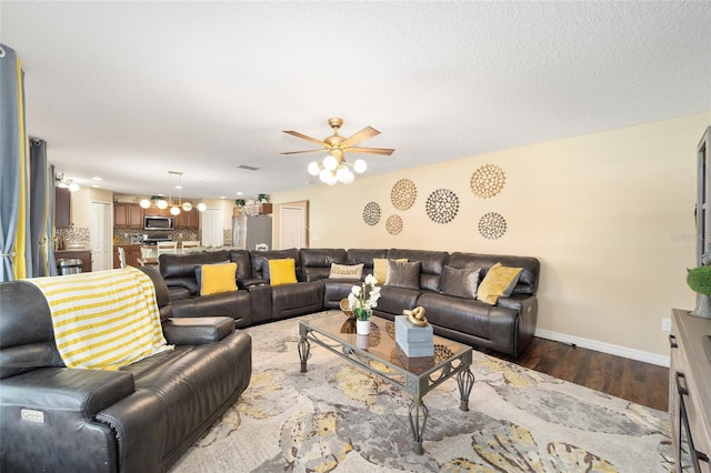 living room featuring visible vents, baseboards, a ceiling fan, dark wood-style floors, and a textured ceiling