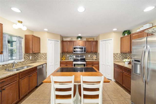 kitchen featuring stainless steel appliances, light tile patterned flooring, a sink, and tasteful backsplash