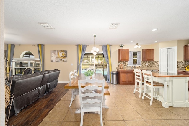 dining area with light tile patterned floors, baseboards, visible vents, and a textured ceiling