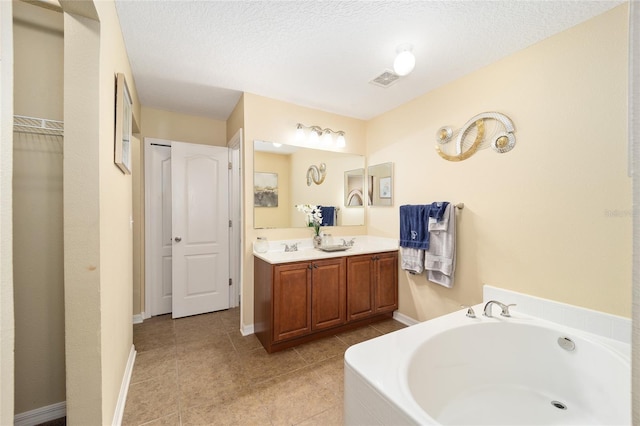 full bath with double vanity, a sink, a textured ceiling, a bath, and tile patterned floors