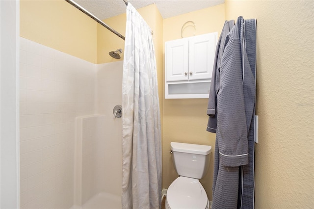 bathroom featuring a textured ceiling, a textured wall, a tile shower, and toilet