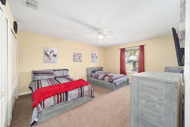 bedroom with a textured ceiling, visible vents, baseboards, a ceiling fan, and carpet