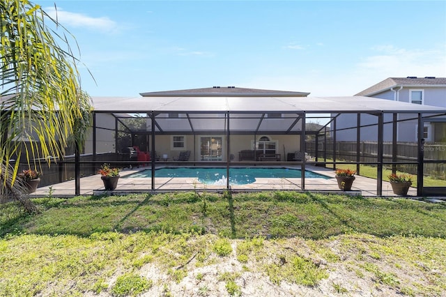 outdoor pool featuring a yard, glass enclosure, and a patio