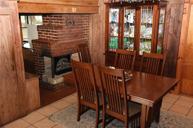 tiled dining room with a fireplace and wooden walls