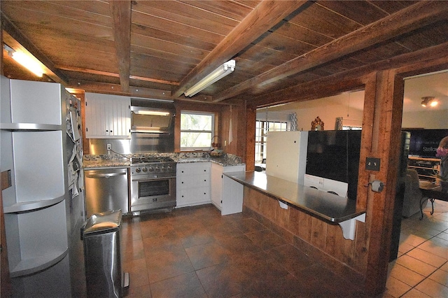 kitchen with white cabinets, wood ceiling, appliances with stainless steel finishes, dark tile patterned floors, and beam ceiling