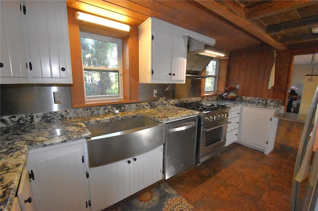 kitchen featuring appliances with stainless steel finishes, a sink, light stone countertops, and white cabinets